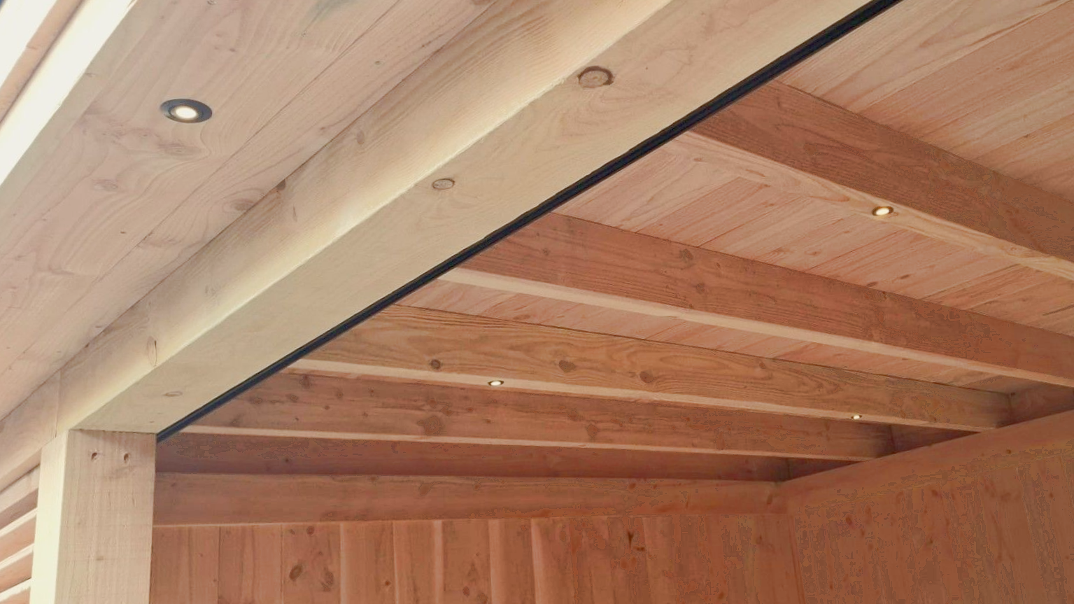 Houten pergolaplafond met inbouwverlichting en donkere rand.