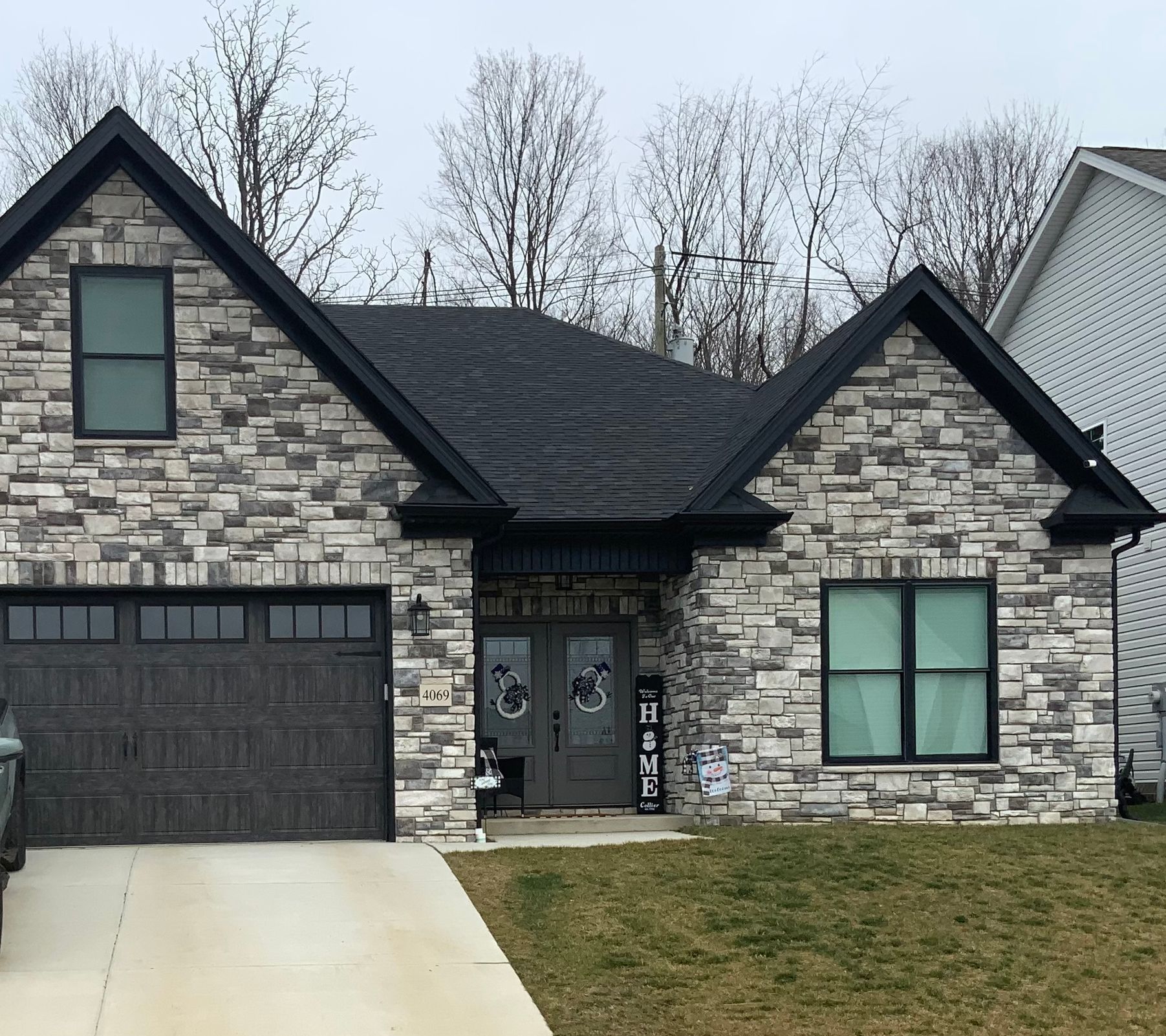 A stone house with a black roof and a black garage door