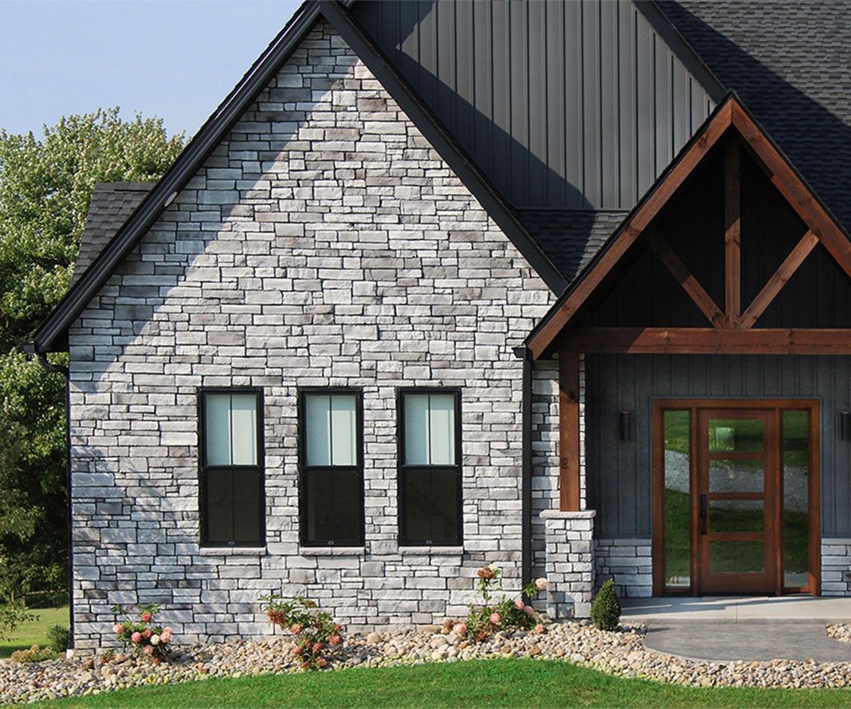 A stone house with black windows and a black roof