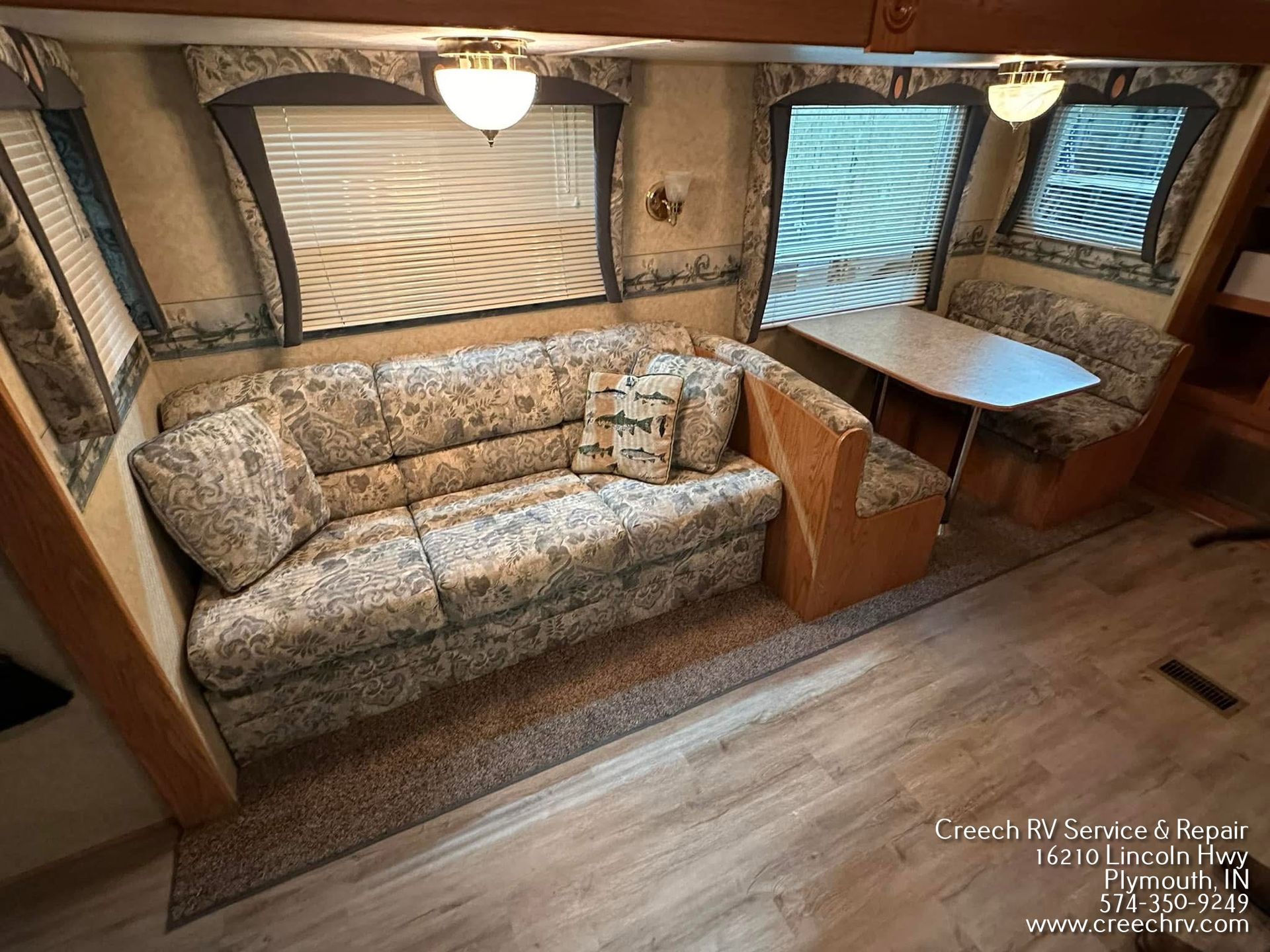 RV roof with air conditioner, vents, and sealant in a repair shop.