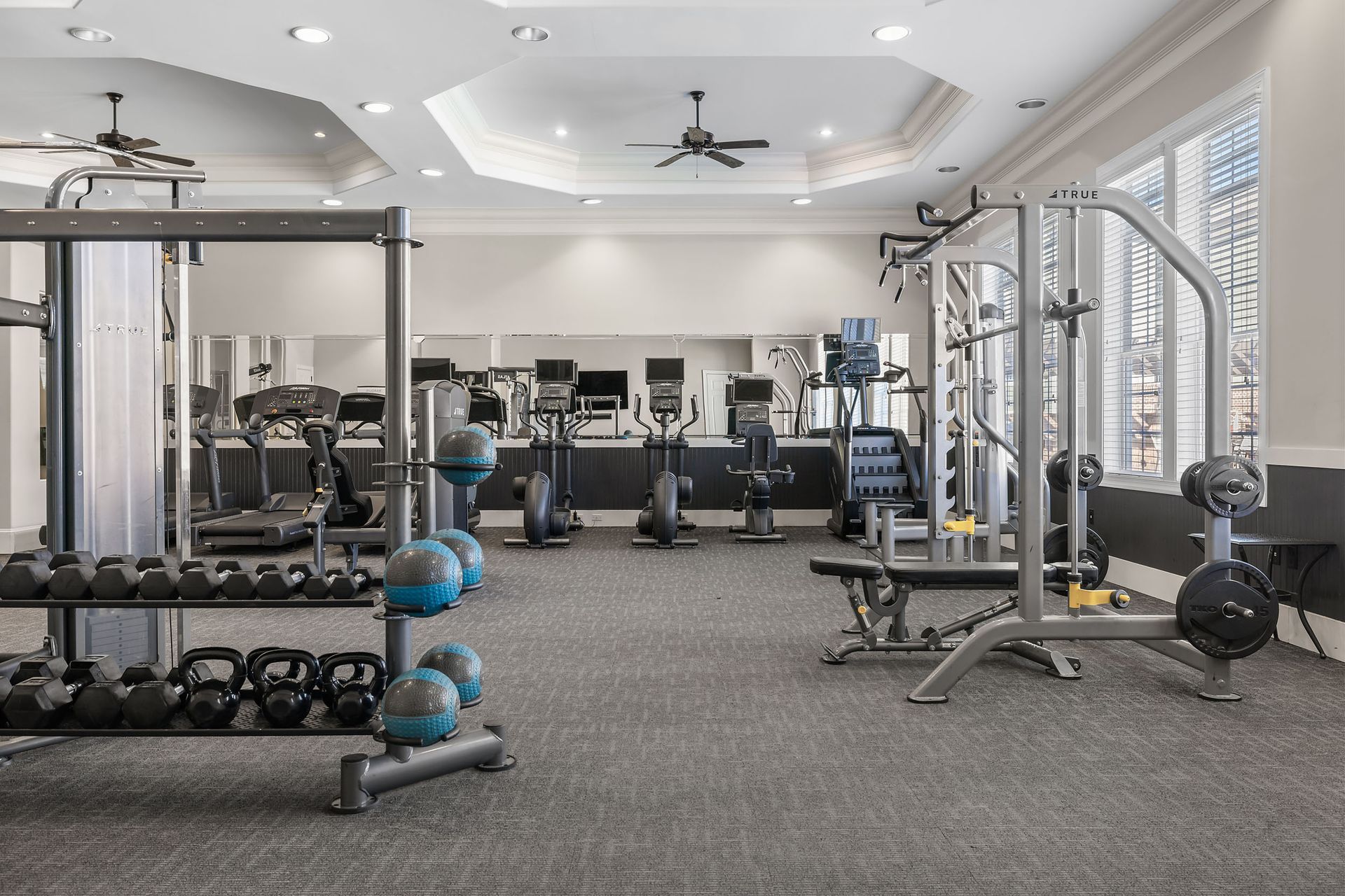 A large gym with a lot of equipment and a ceiling fan at Marquis Ellis Crossing offers Durham apartments for rent in NC.