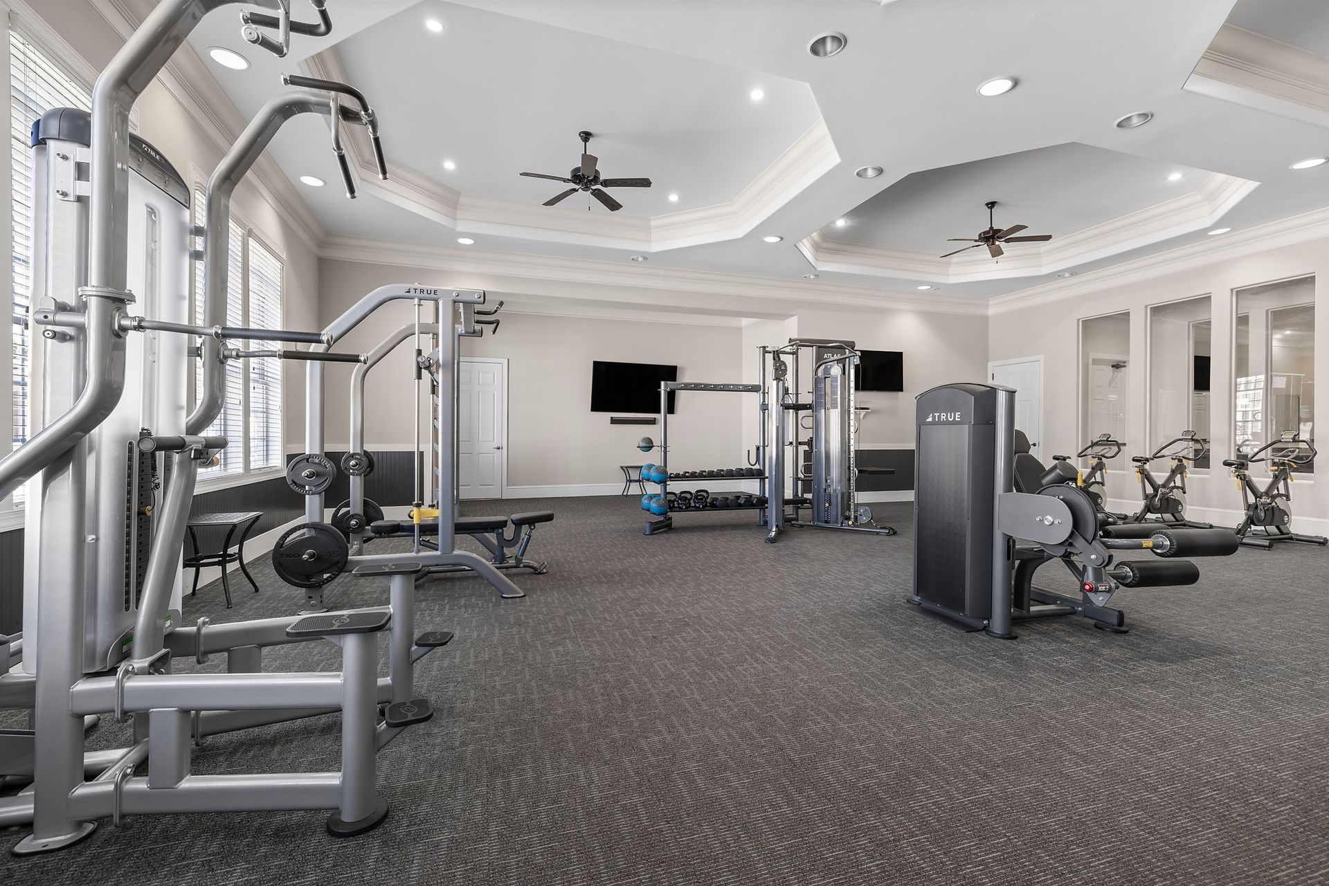 A large gym with a lot of equipment and a ceiling fan at Marquis Ellis Crossing offers apartments for rent near Research Triangle Park, Durham, NC.