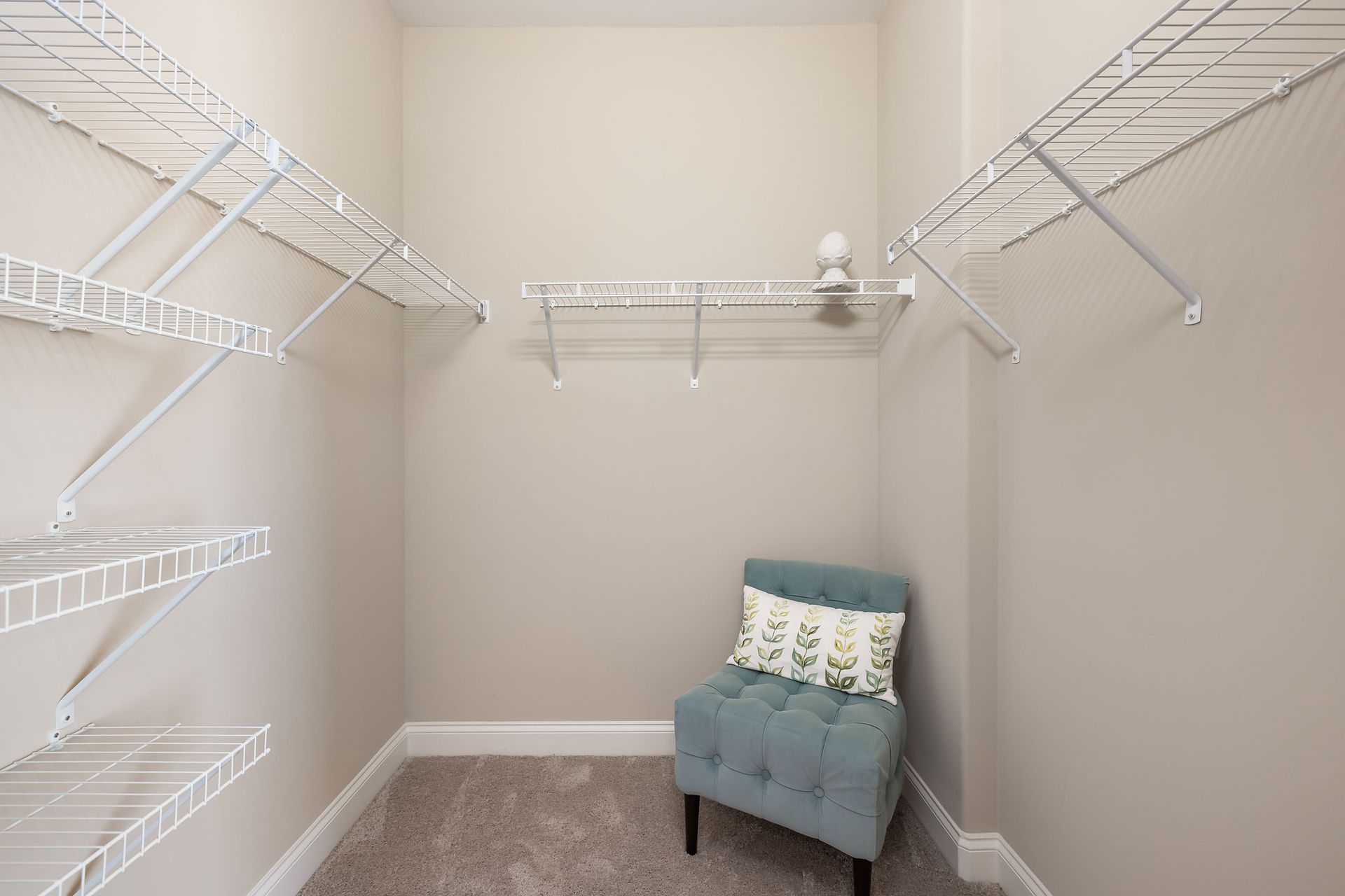 A walk in closet with lots of shelves and a chair at Marquis Ellis Crossing offers apartments in Durham, NC.