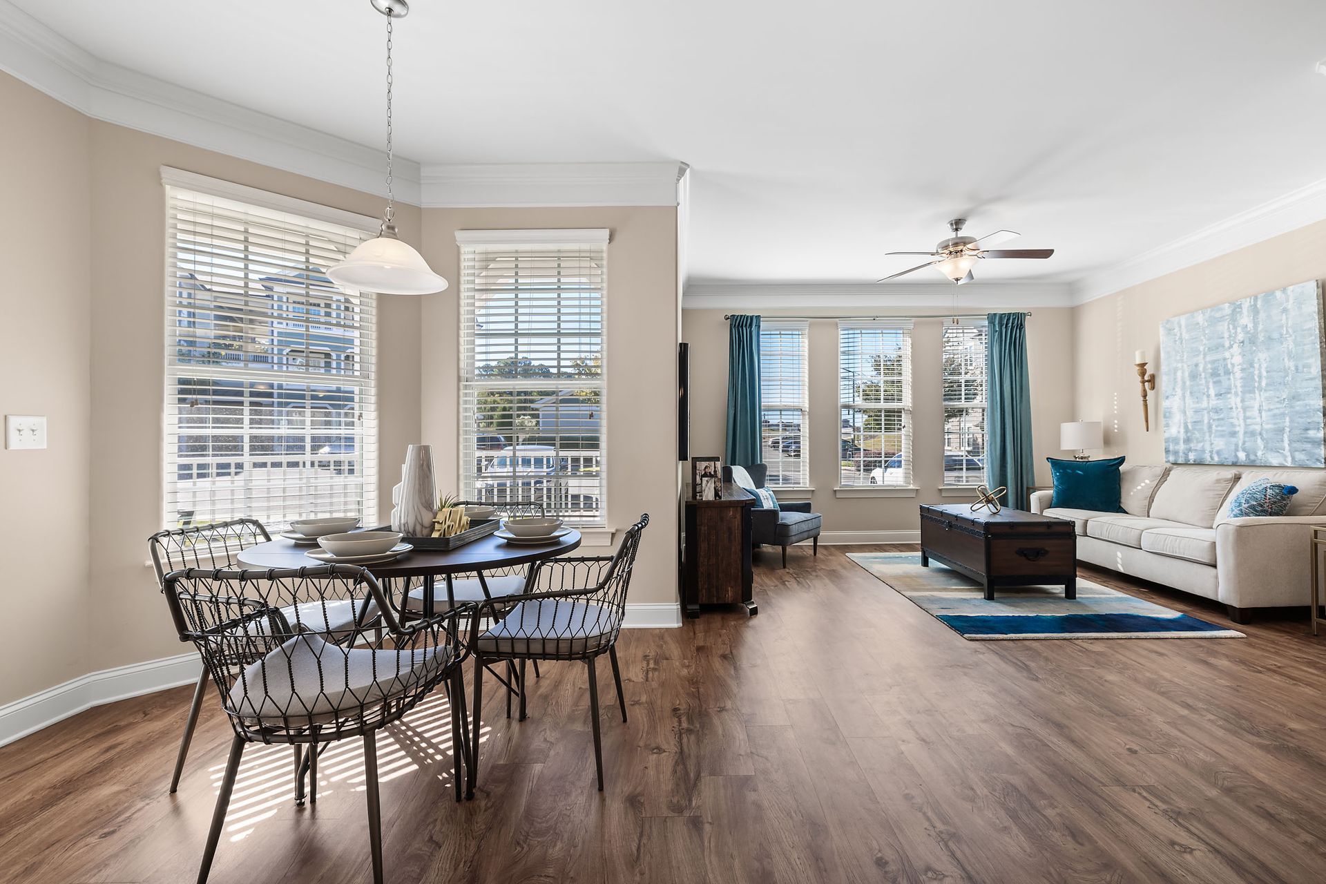 A living room with a dining table and chairs, a couch, and a ceiling fan at Marquis Ellis Crossing offers apartments for rent near Duke University, Durham, NC.