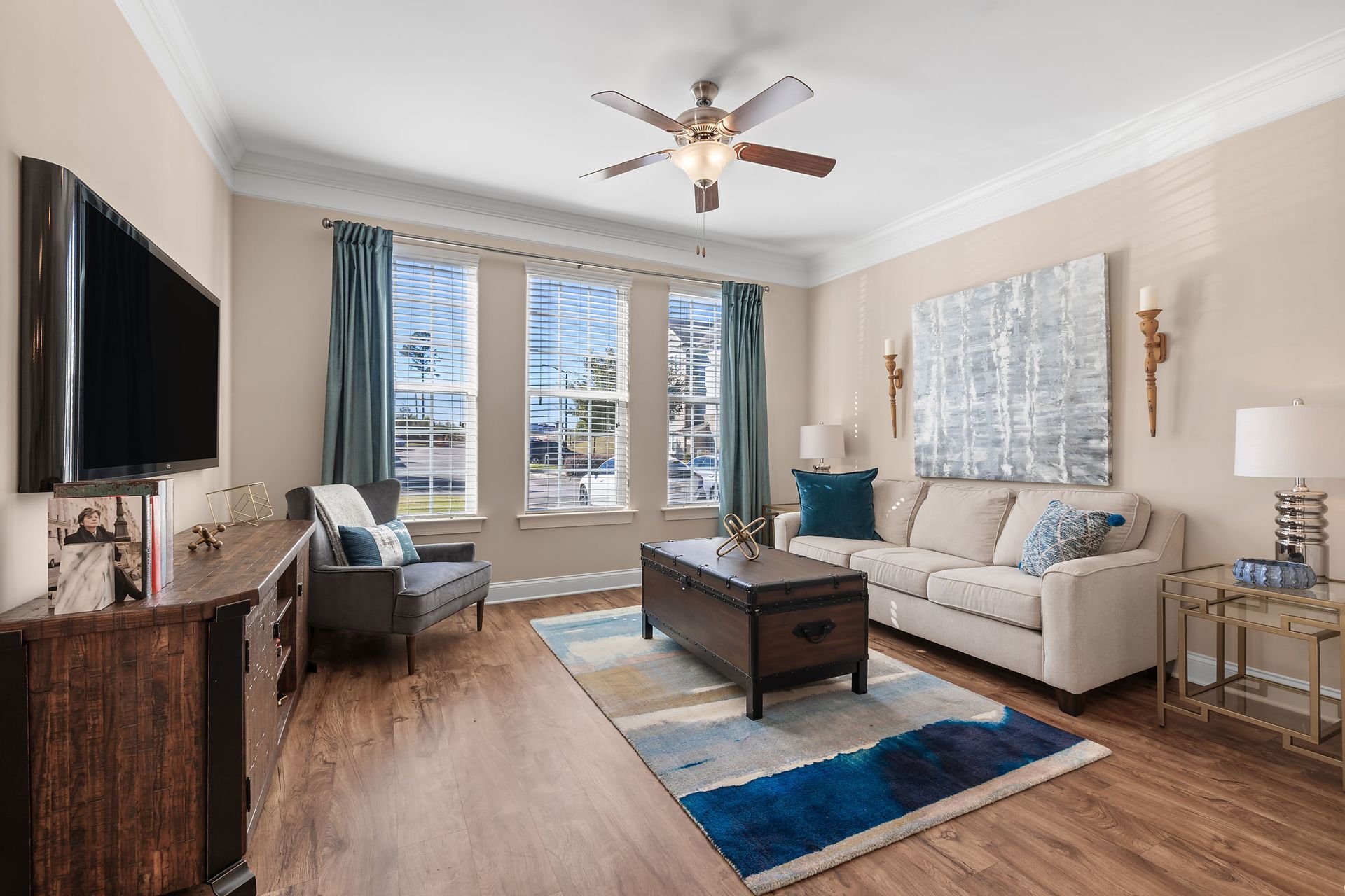 A living room with a couch, chair, coffee table, television and ceiling fan at Marquis Ellis Crossing offers apartments for rent in Durham, NC.