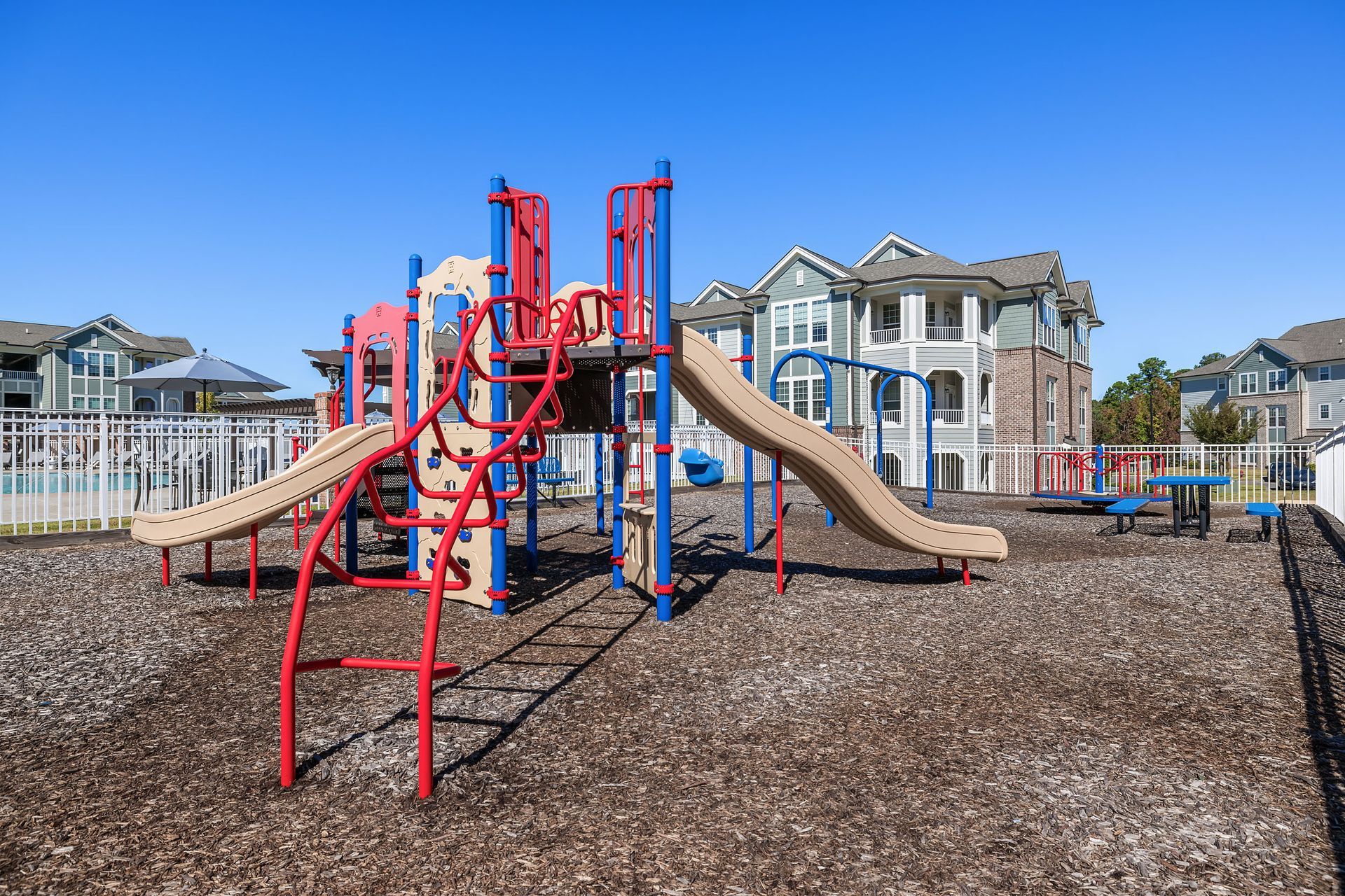 A colorful playground in front of a row of apartment buildings at Marquis Ellis Crossing offers apartments for rent in Durham, NC.