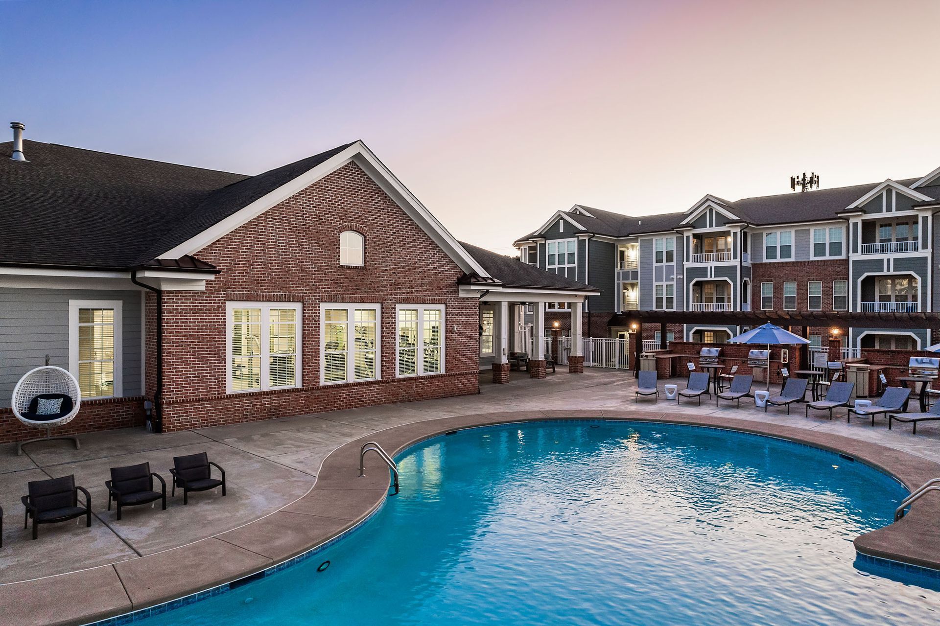There is a large swimming pool in front of a brick building at Marquis Ellis Crossing offers apartments for rent near Triangle Park, Durham, NC.