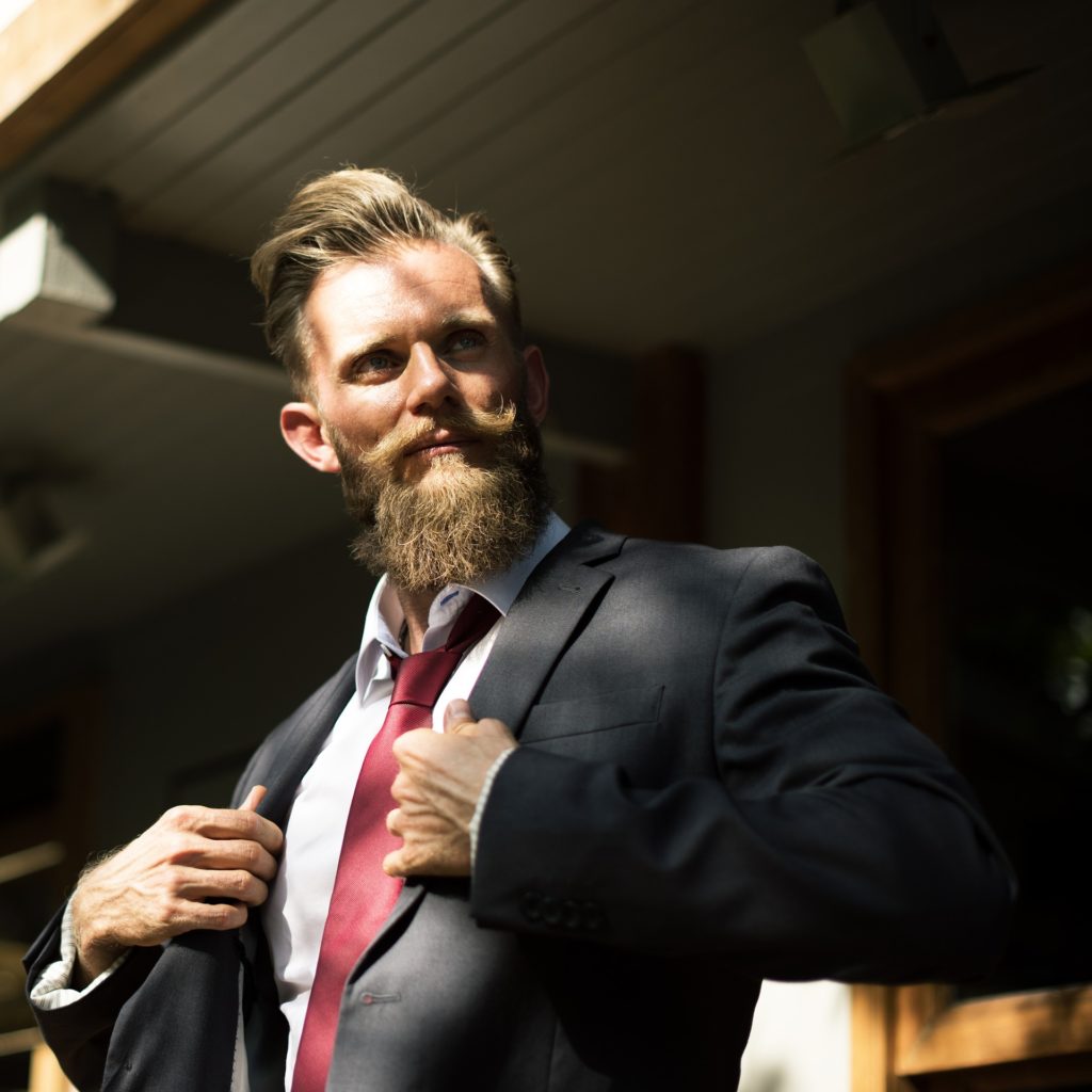 Un uomo con barba e baffi indossa un abito e una cravatta