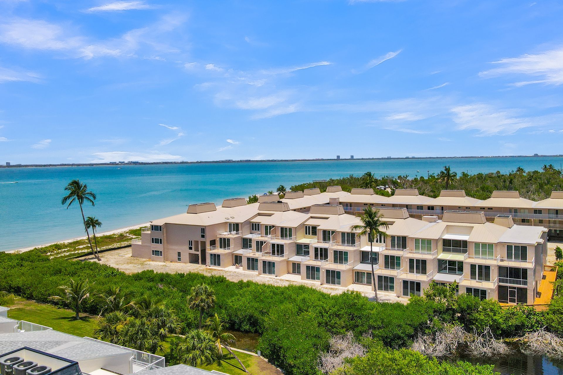 Beachfront resort building with palm trees, turquoise water, and clear blue sky