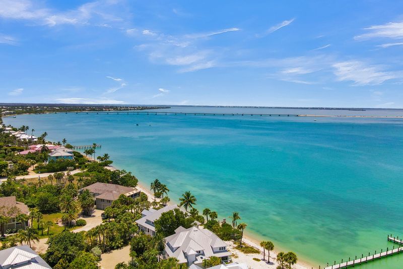 Aerial view of a turquoise ocean, sandy shore, and tropical resort with palm trees under a blue sky Aerial view of a turquoise ocean, sandy shore, and tropical resort with palm trees under a blue sky