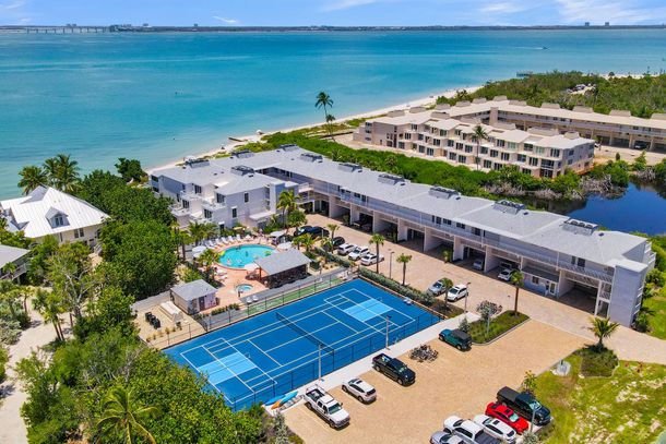 Aerial view of a turquoise beach beside a resort with pools and white buildings Aerial view of a turquoise beach beside a resort with pools and white buildings