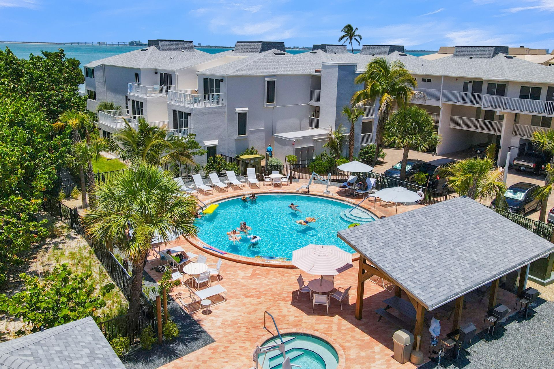 Resort pool courtyard with white buildings, palm trees, and a shaded hot tub cabana