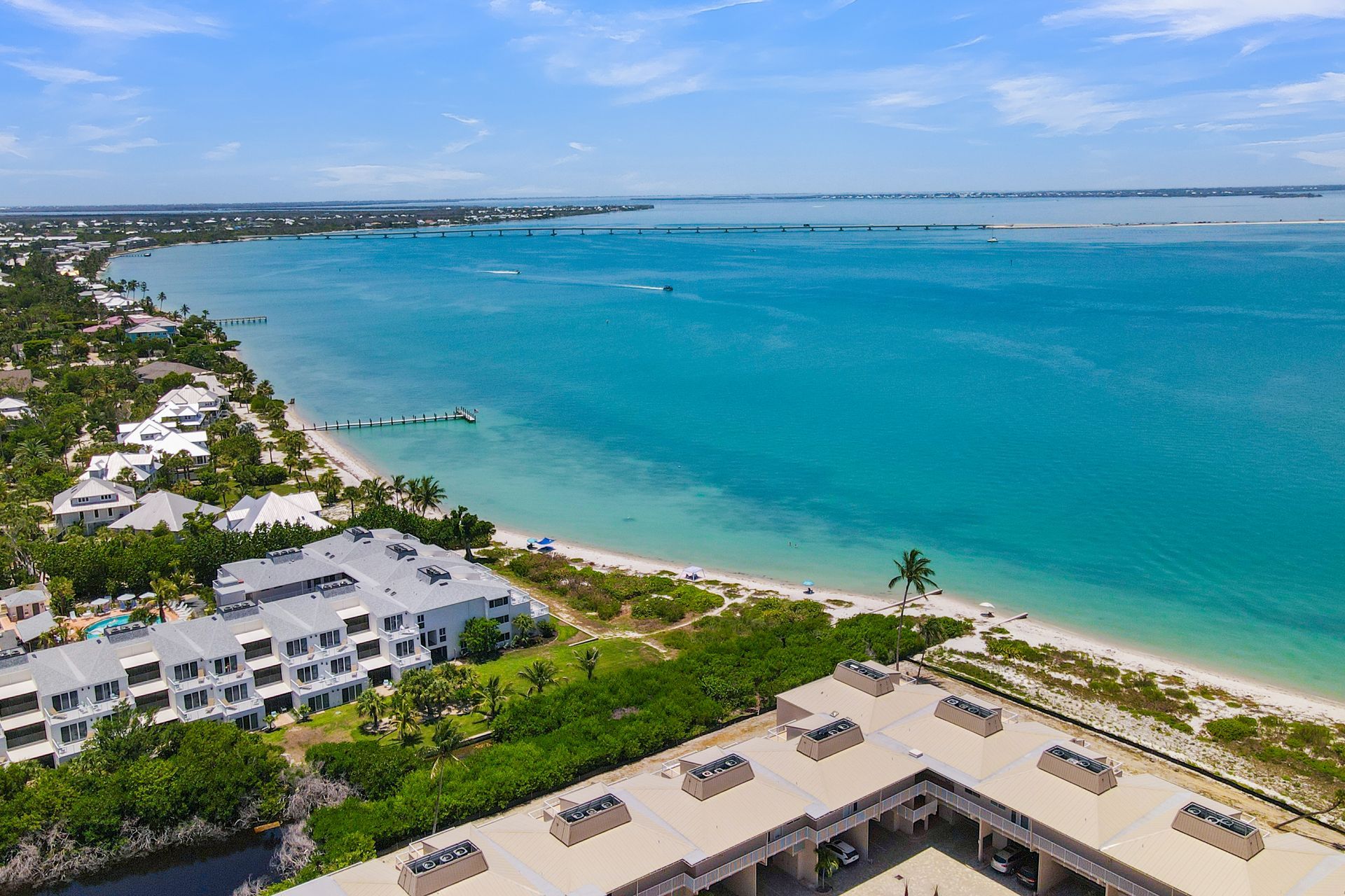 Coastal resort condos beside a palm-lined lagoon under a bright blue sky