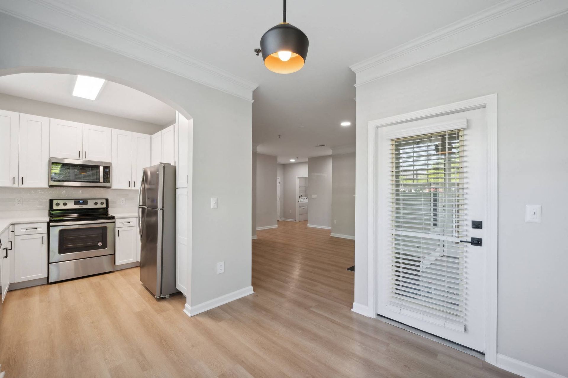 a renovated kitchen and living room with white cabinets and a door to a hallway