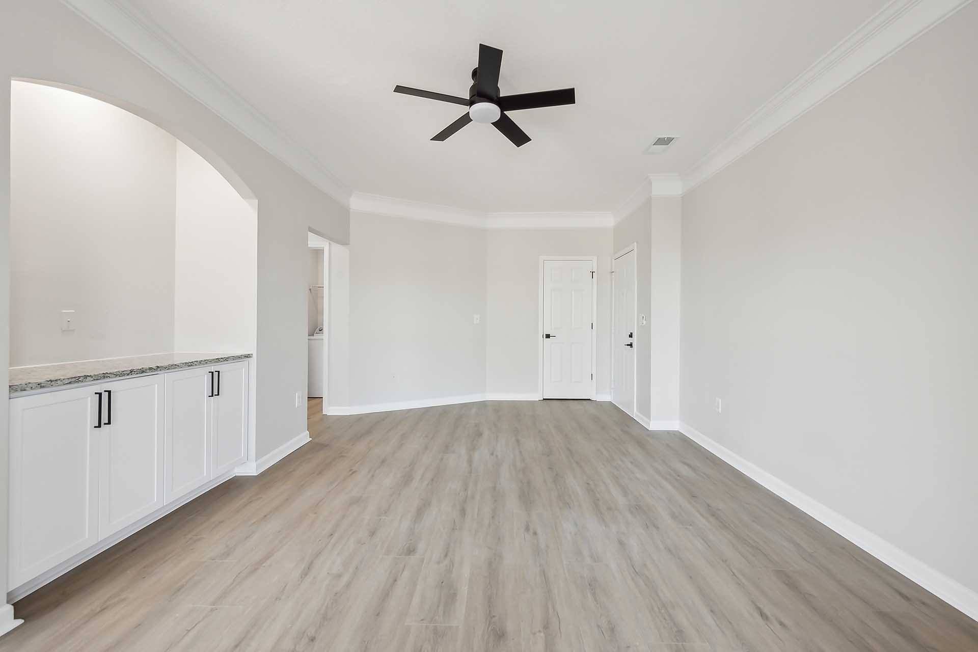 A spacious room with a ceiling fan and light wood flooring.