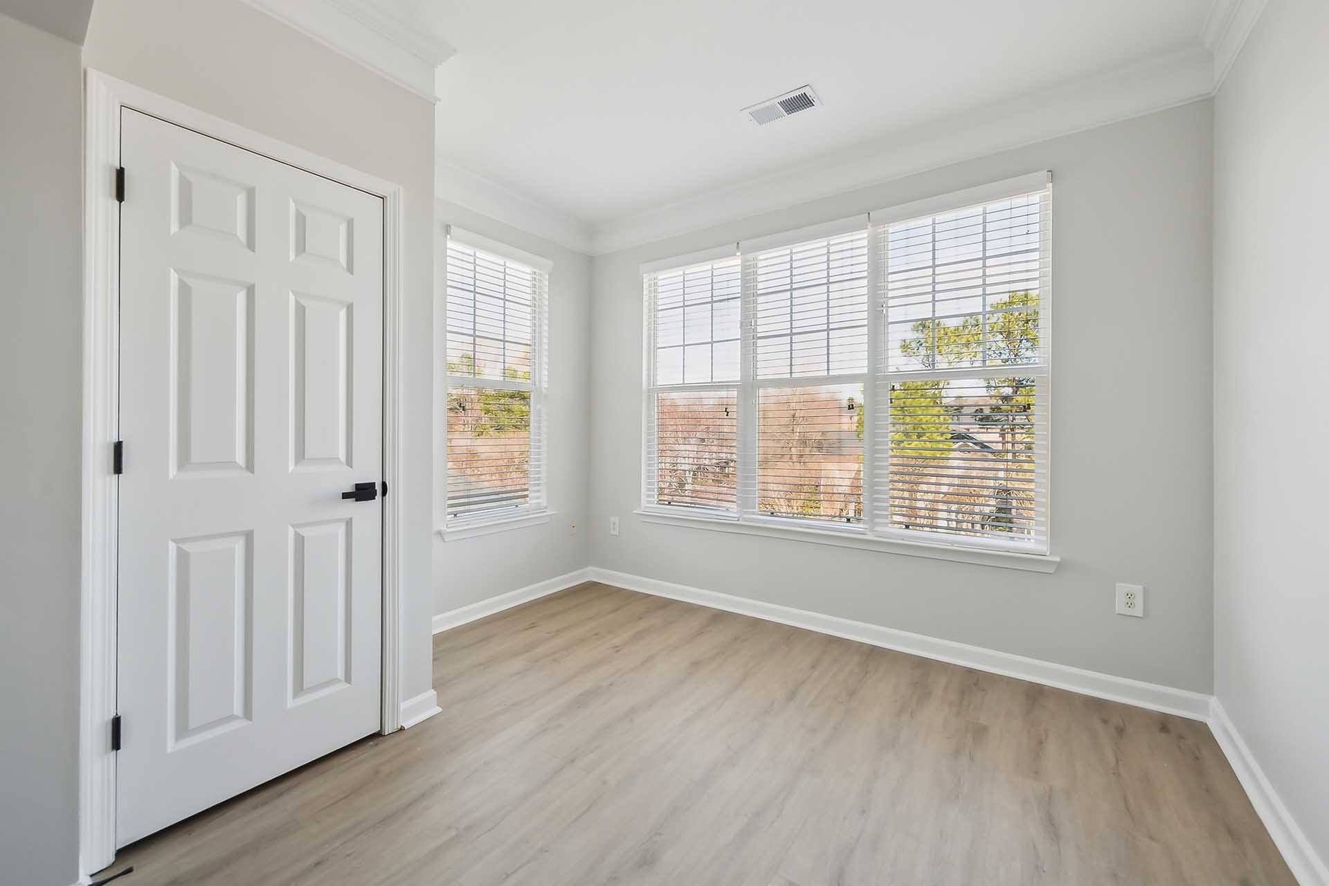 A room with a white door and a window with blinds.