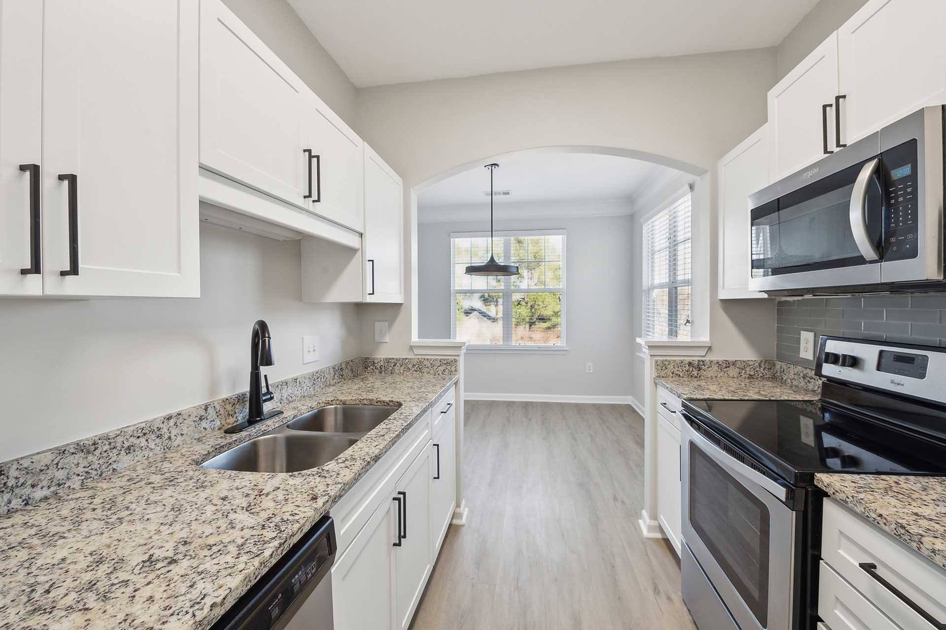 A kitchen with granite countertops and white cabinets.