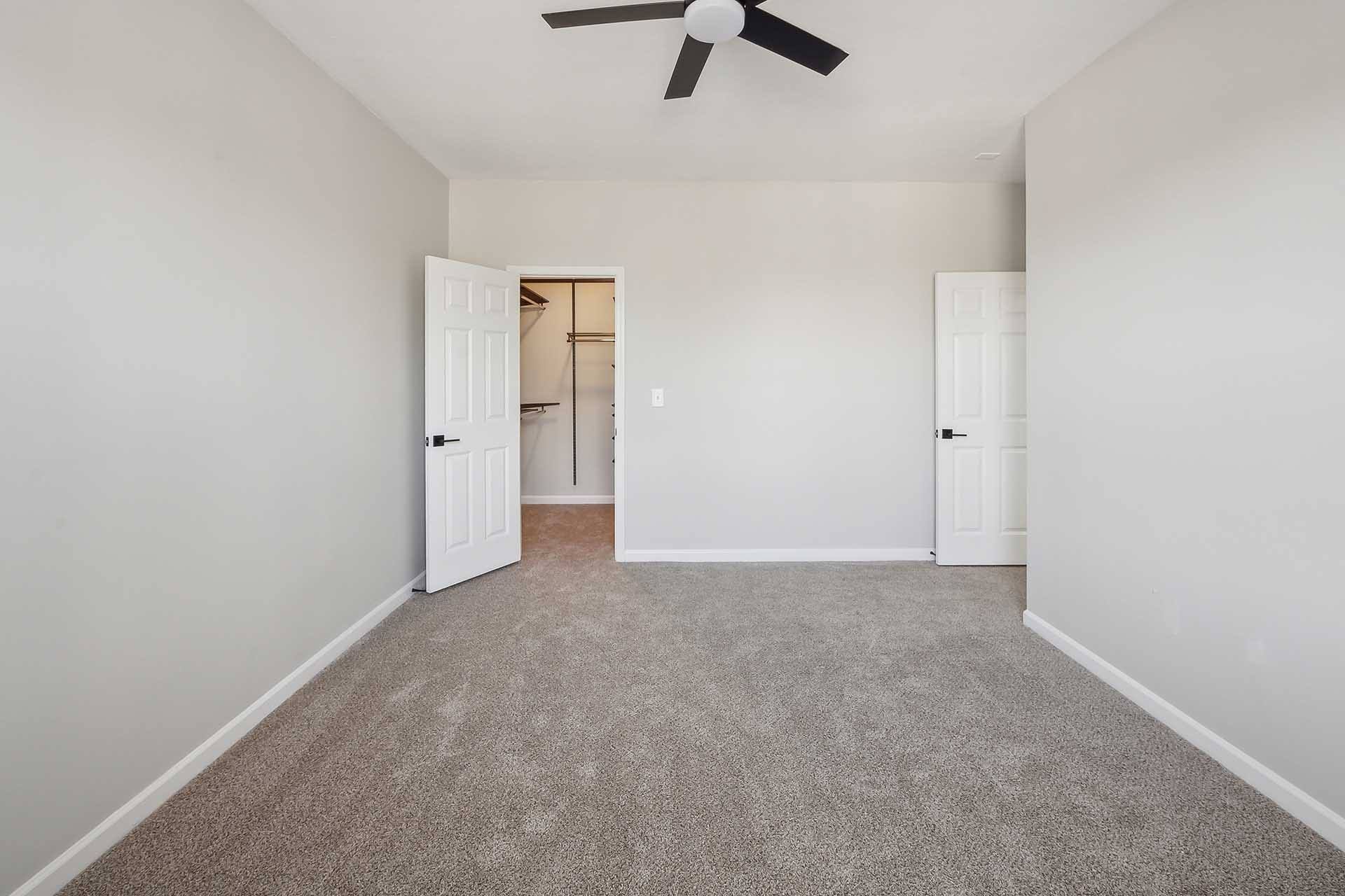 A room with a ceiling fan and carpeted floor.