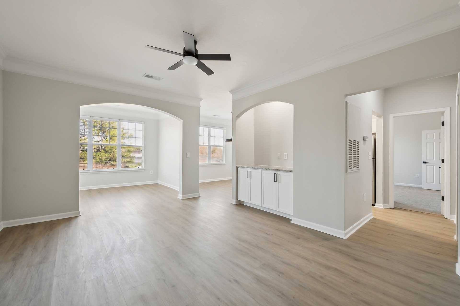 A spacious room with a ceiling fan and light wood flooring.