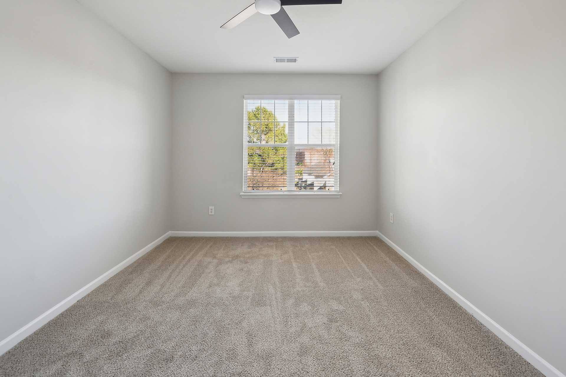 A room with a window and a fan on the ceiling.