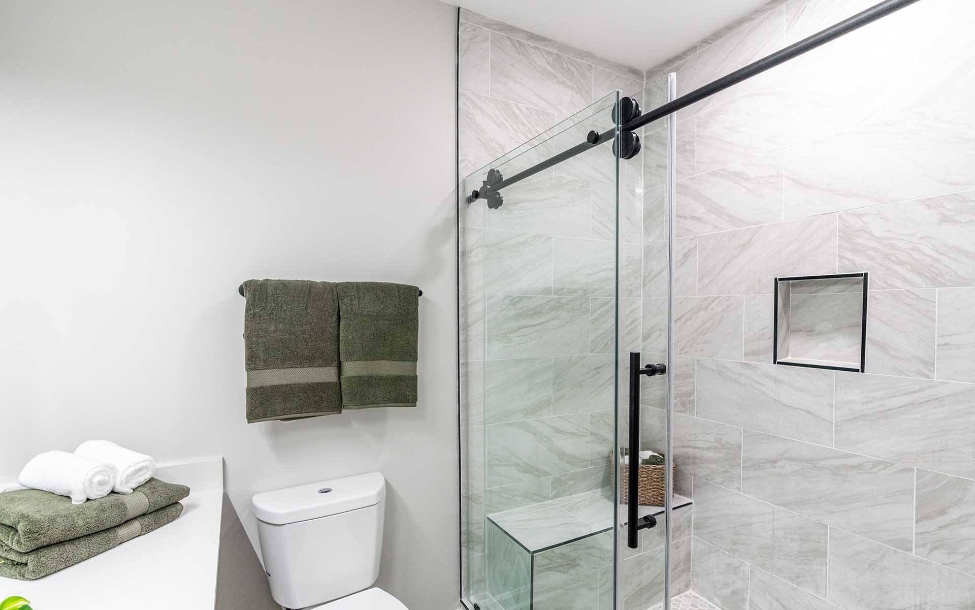 A bathroom with a toilet, a towel, and a glass shower door.