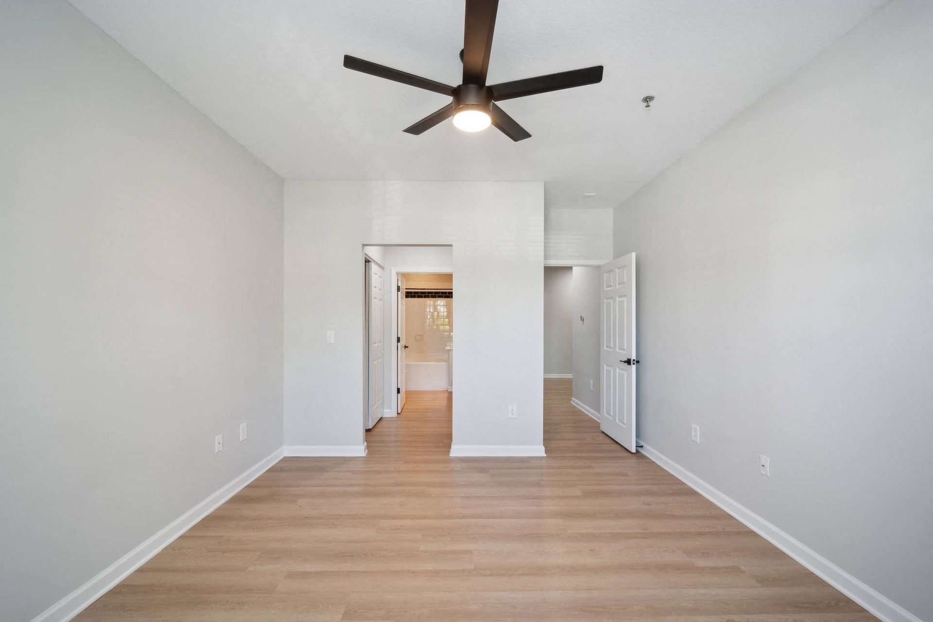 a living room with white walls and a ceiling fan