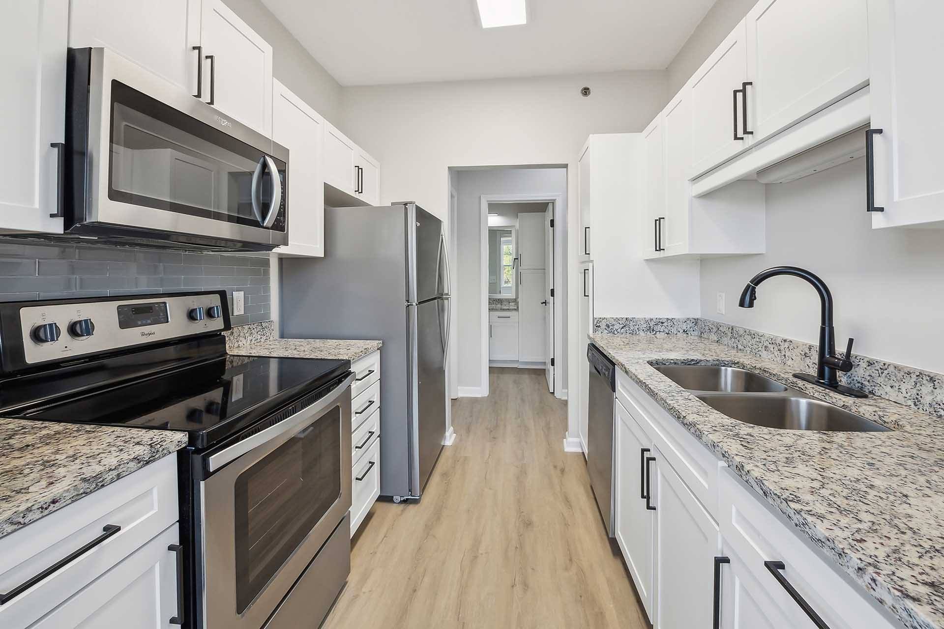 A kitchen with white cabinets and granite countertops.