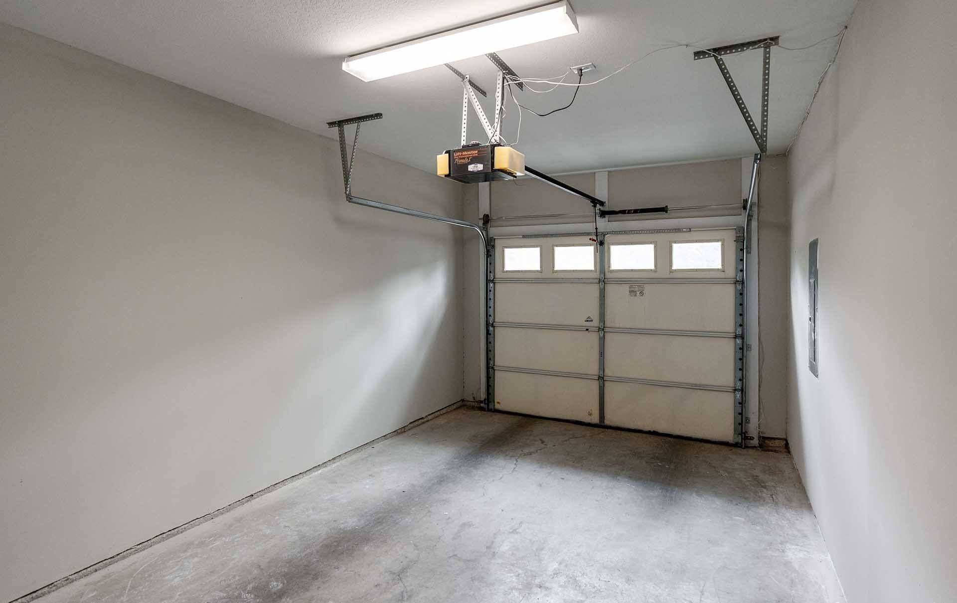 A garage with a white wall and a grey floor.