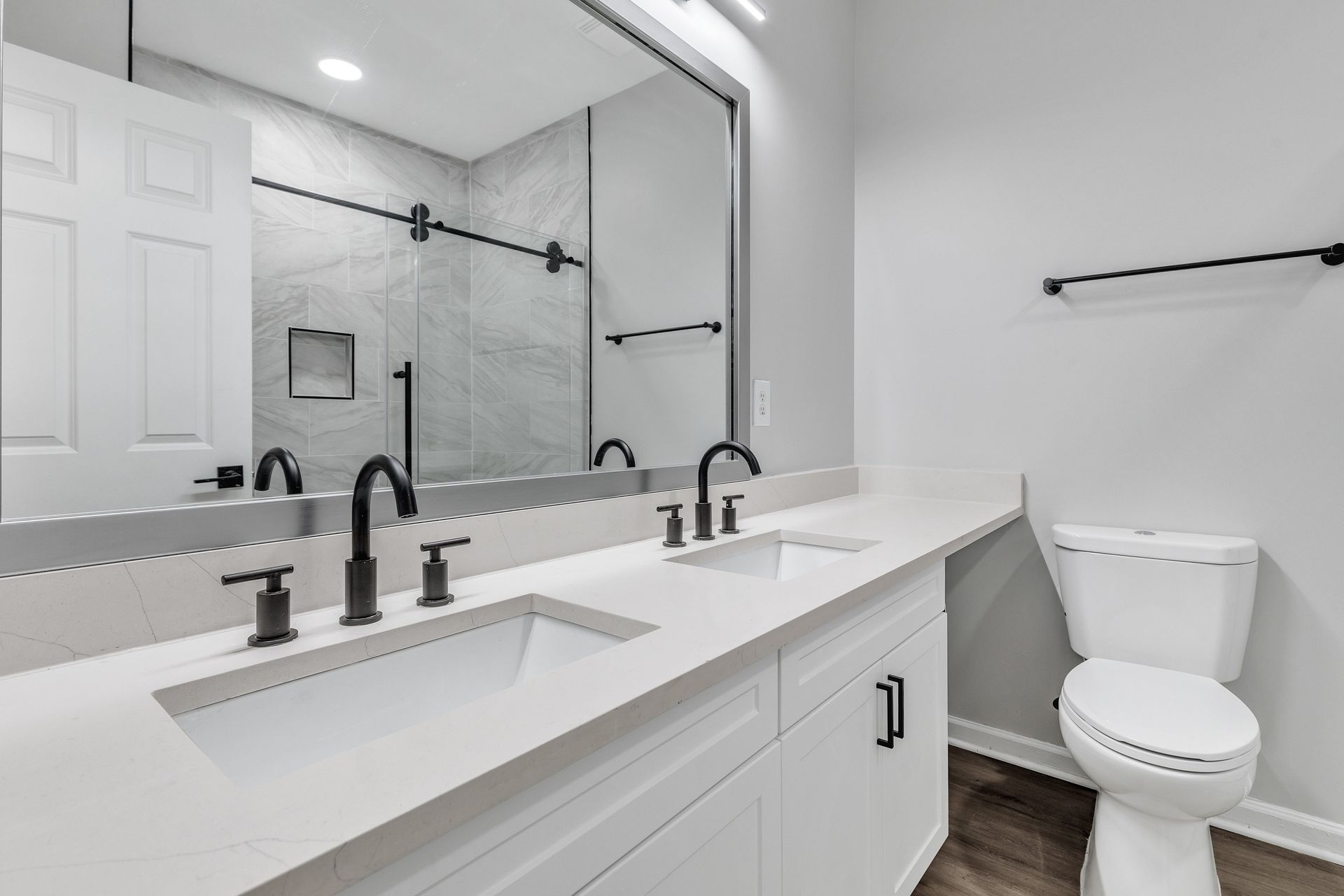 A white bathroom with a toilet, sink, and mirror.