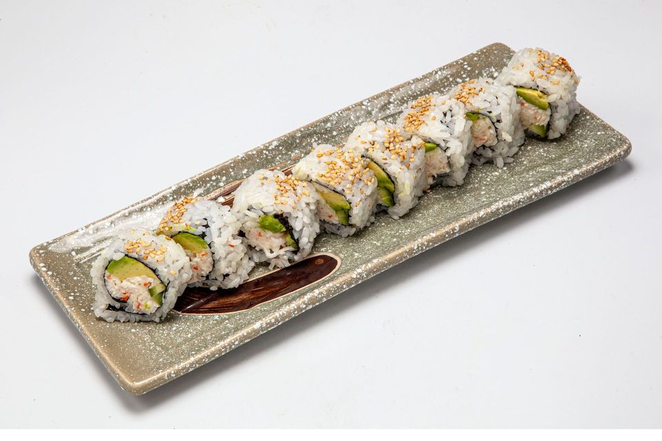 Sushi roll slices on a rectangular gray plate with sauce garnish