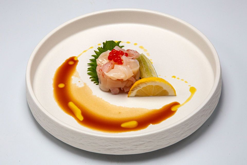 Elegant plated appetizer with shrimp, lemon wedge, and herb garnish on a white dish