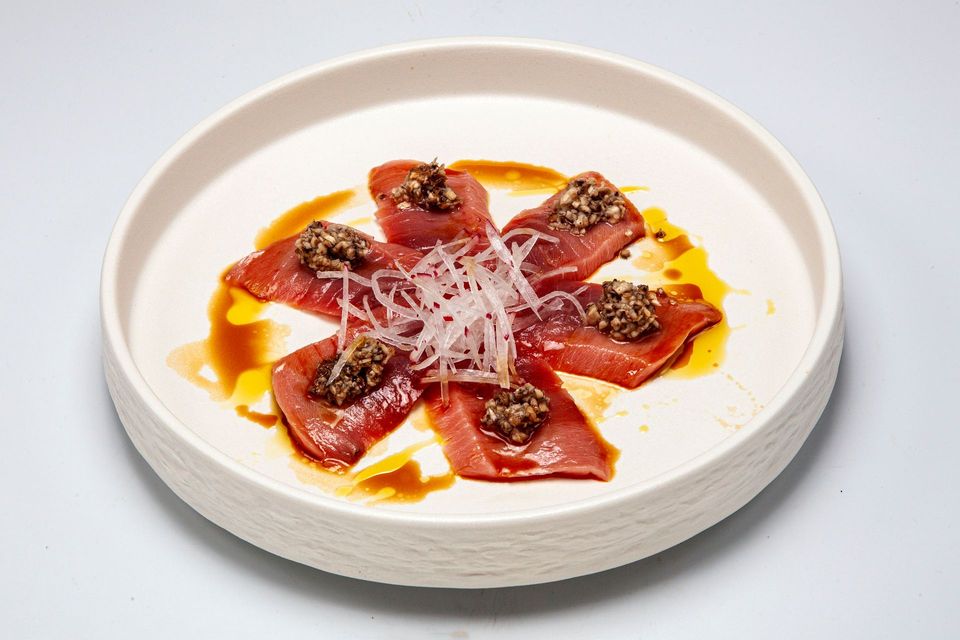 Beef carpaccio with shaved cheese and balsamic on a white plate