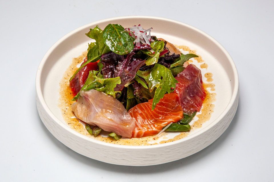 Gourmet fish sashimi with greens on a white plate