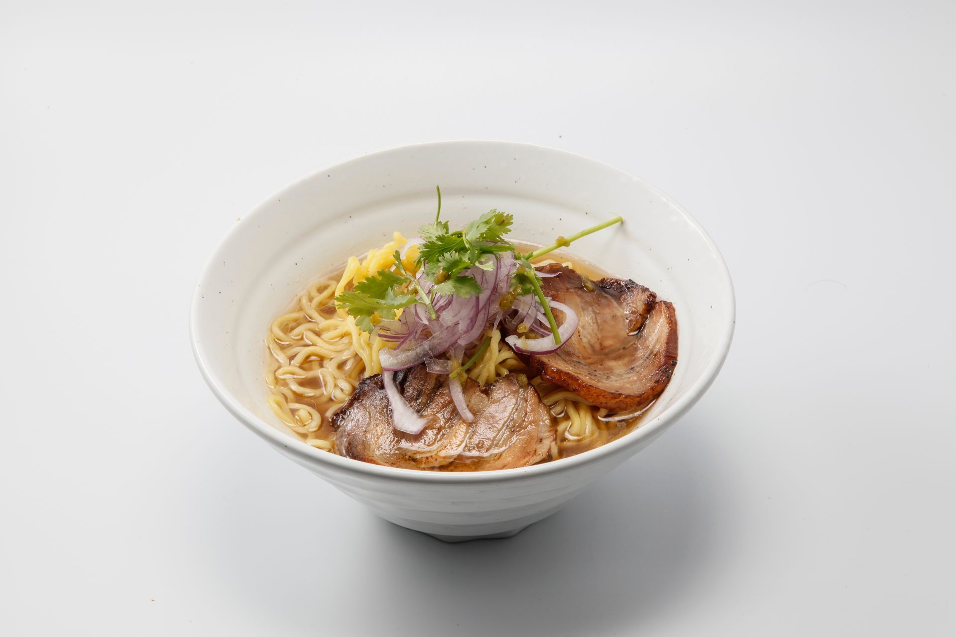 Ramen bowl with sliced pork, noodles, egg, and green onions in a white bowl