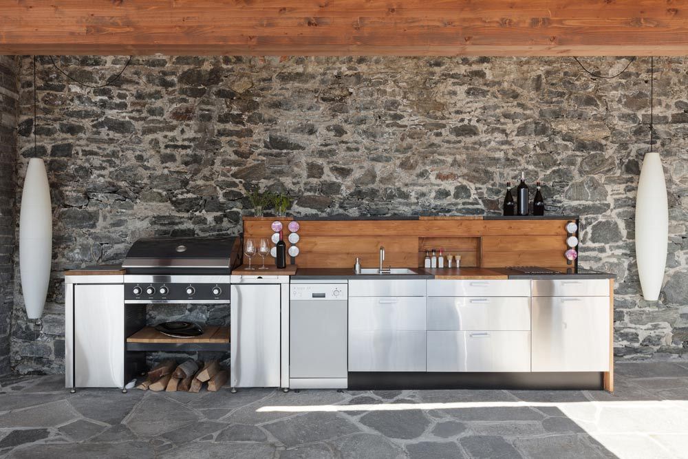 A Kitchen With Stainless Steel Cabinets and a Stone Wall — Allnew Kitchens in Charmhaven, NSW