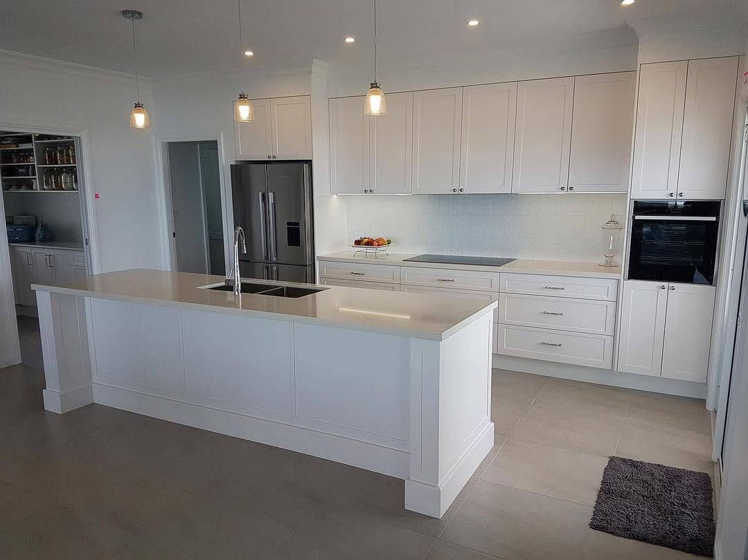 White modern kitchen with island, cabinets, stainless steel refrigerator, and built-in oven. — Allnew Kitchens in Charmhaven, NSW