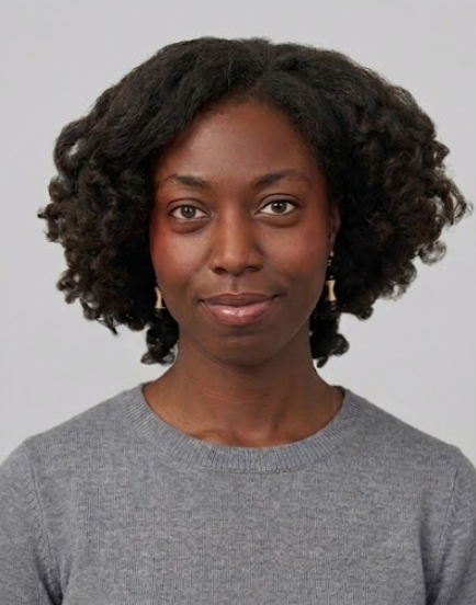 Portrait of a person with curly hair wearing a gray sweater against a neutral background
