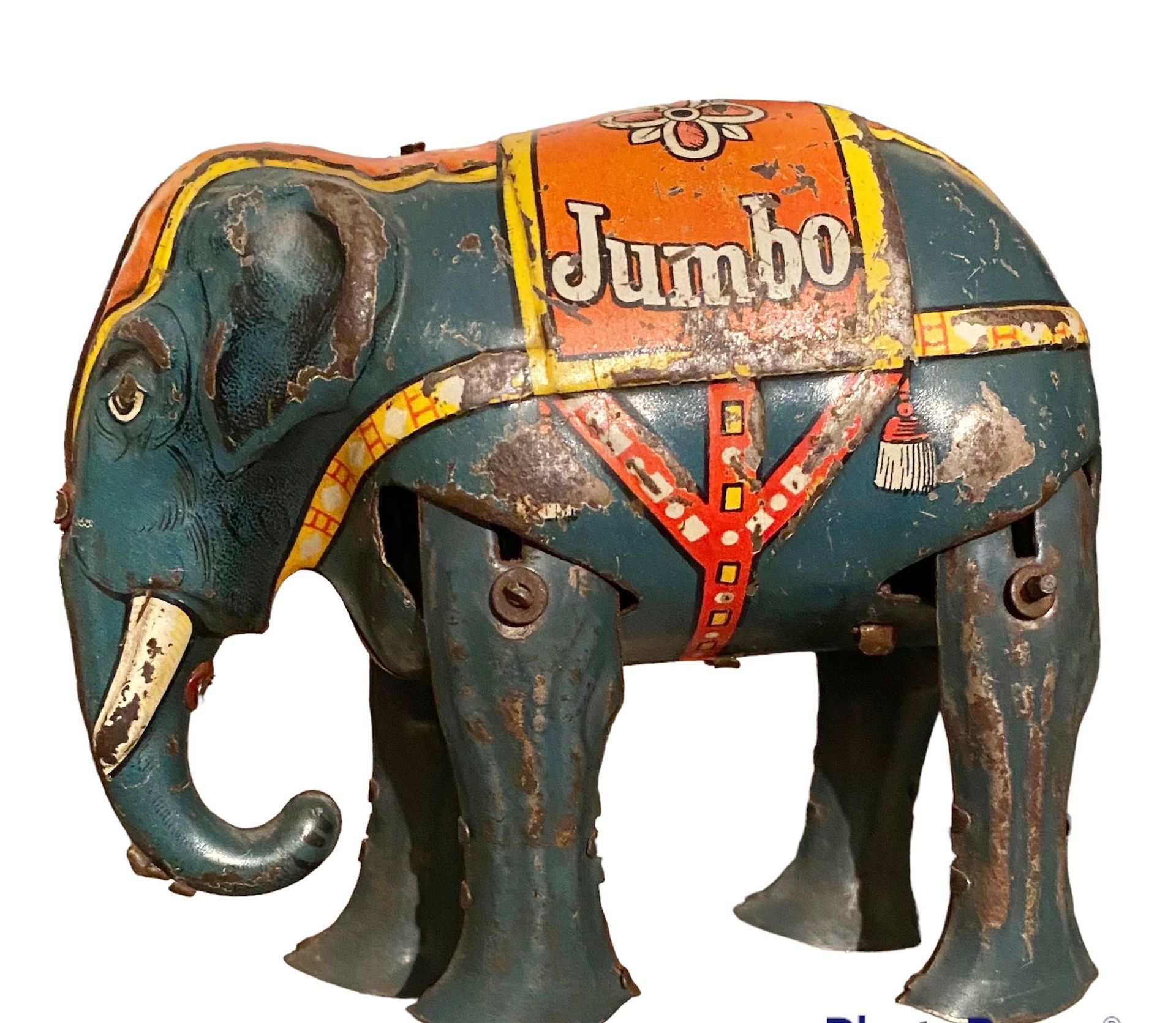 Een vintage tinnen speelgoedolifantje, blauw geverfd met een oranje dekentje waarop het woord 