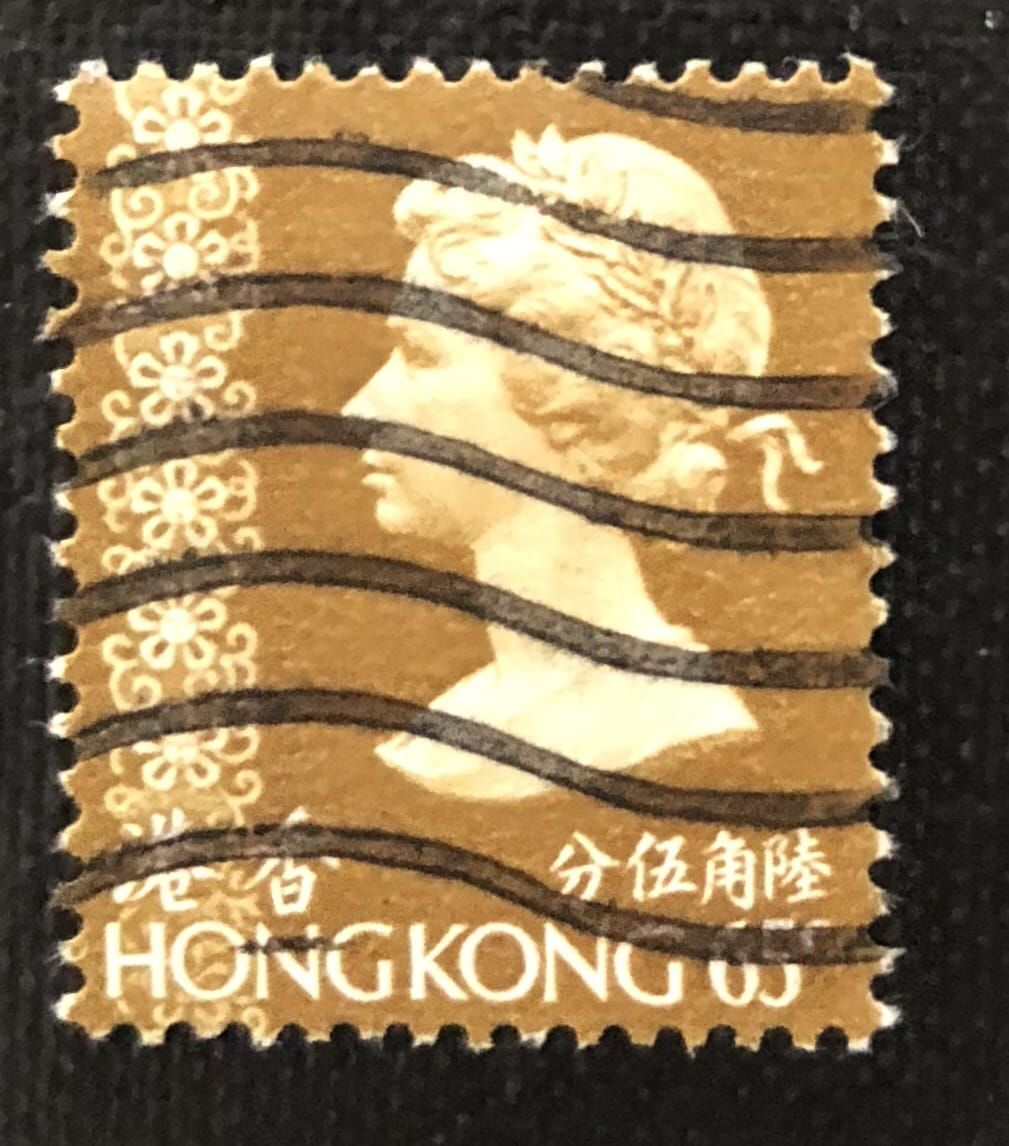 Een postzegel uit Hongkong van 65 cent met een zijprofiel van koningin Elizabeth II, versierd met bruin-witte bloemmotieven.