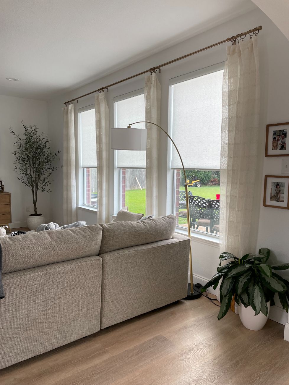 Living room with a beige couch, tall windows with curtains, and a floor lamp.
