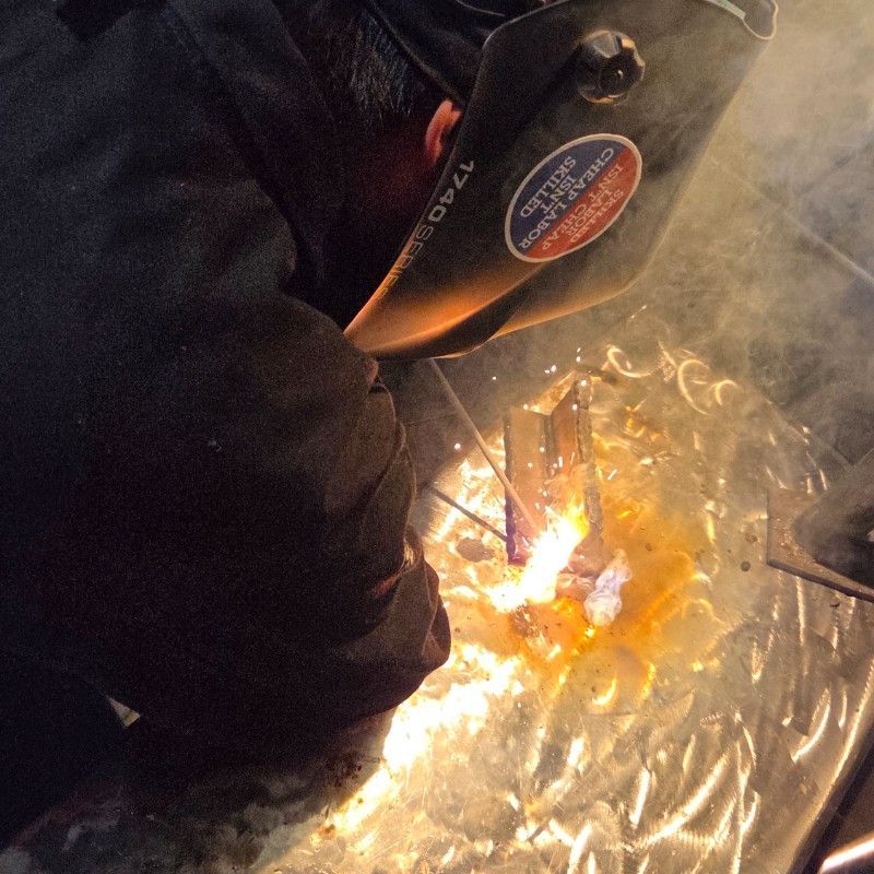 Welder with mask welding metal, bright sparks and glow.