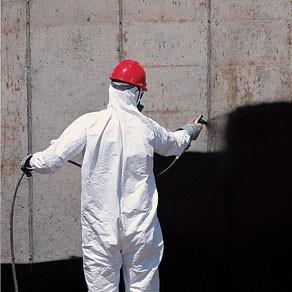 man spraying foundation to waterproof basement