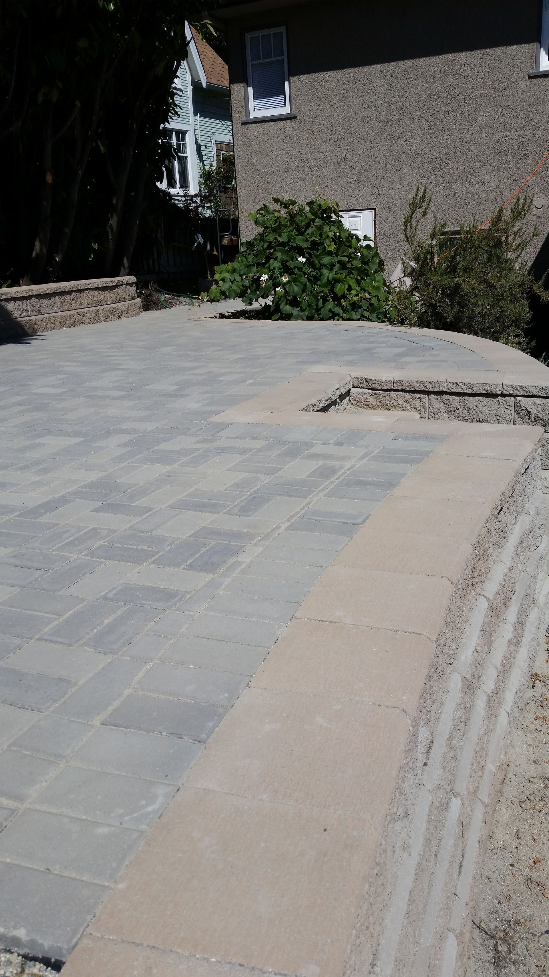Interlocking paver patio with allan block retaining wall in the backyard of a Victoria home, patio construction by Larix Landscape
