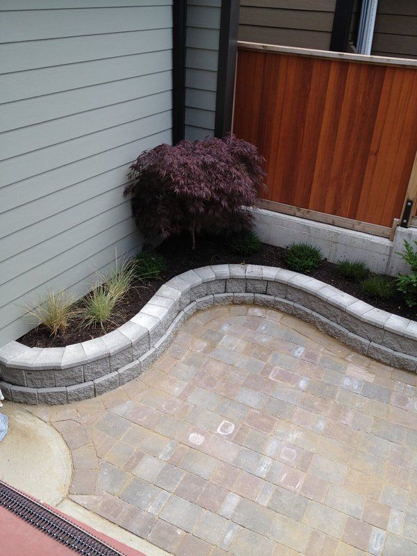 Small brick walled garden wall for garden in corner of house with paved walkway
