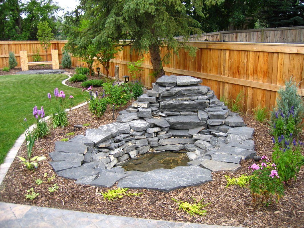 A pond in a garden for water drainage with a new fence installed behind it