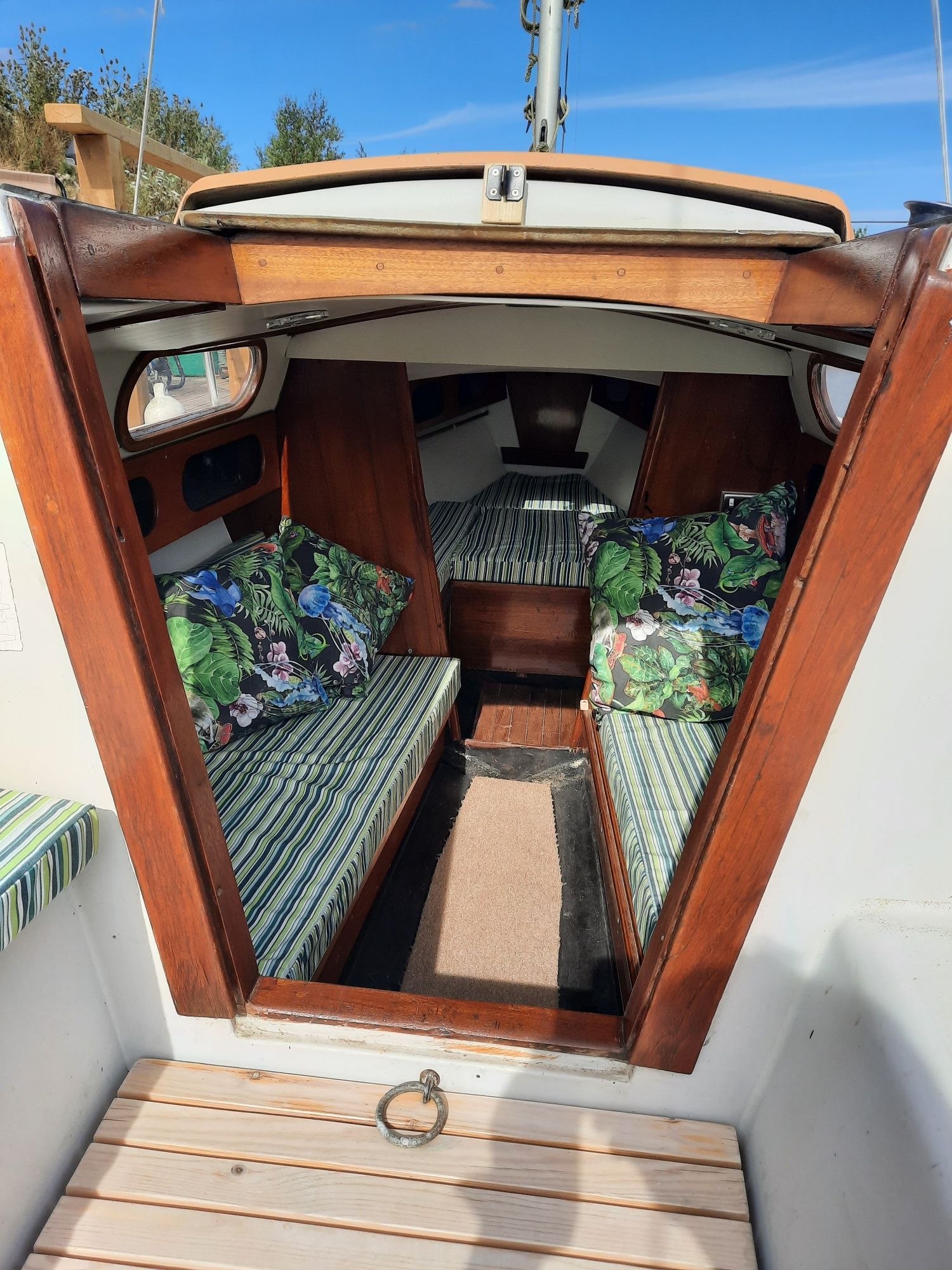 The inside of a small boat with a wooden deck and cushions.