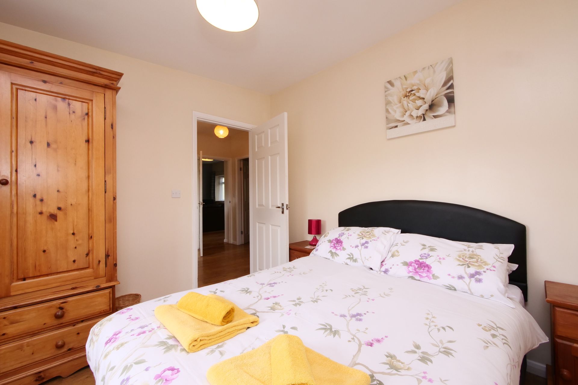 A bedroom with a large bed and a wooden wardrobe