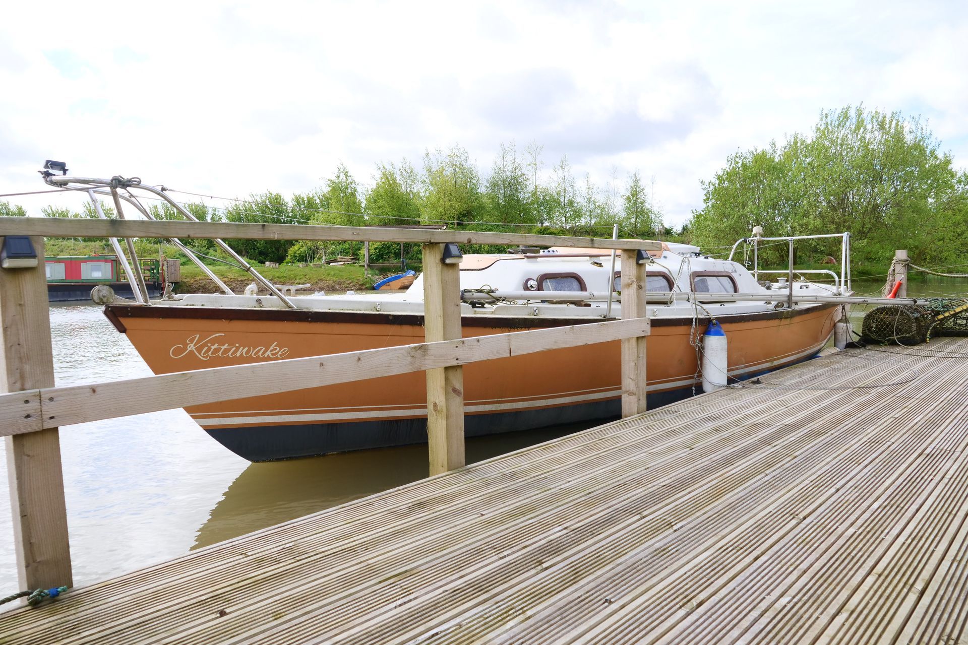 A boat is docked on a wooden dock next to a body of water.
