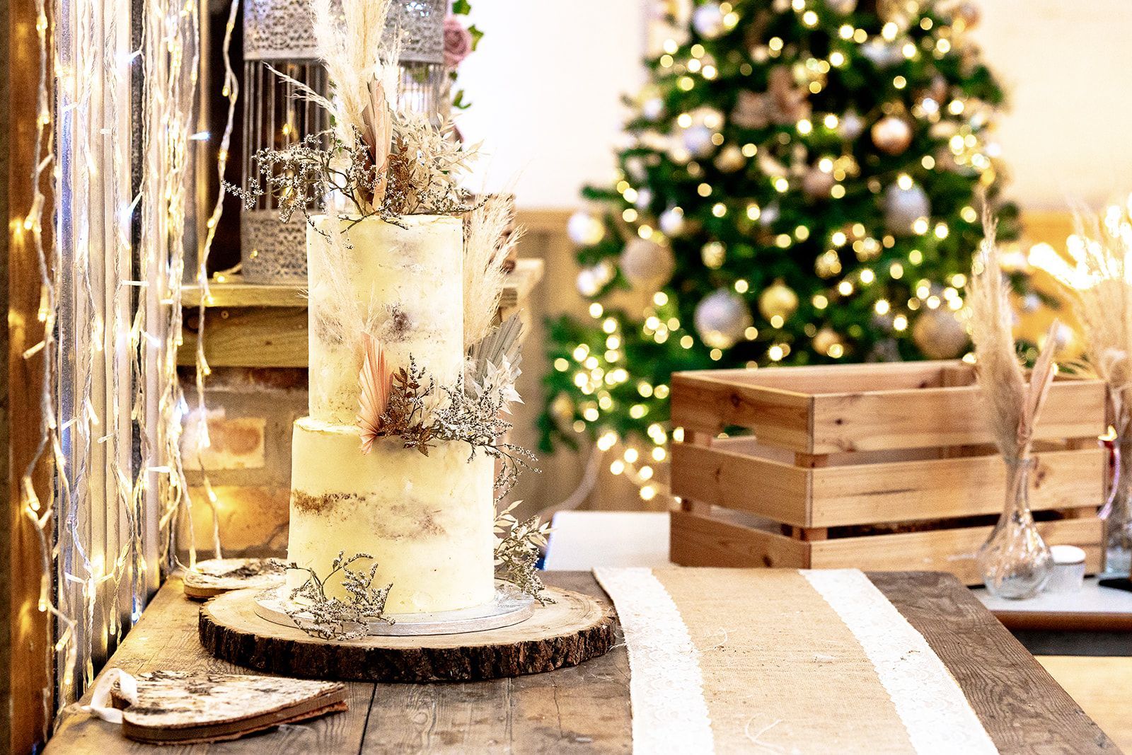 A cake is sitting on a wooden table in front of a christmas tree.