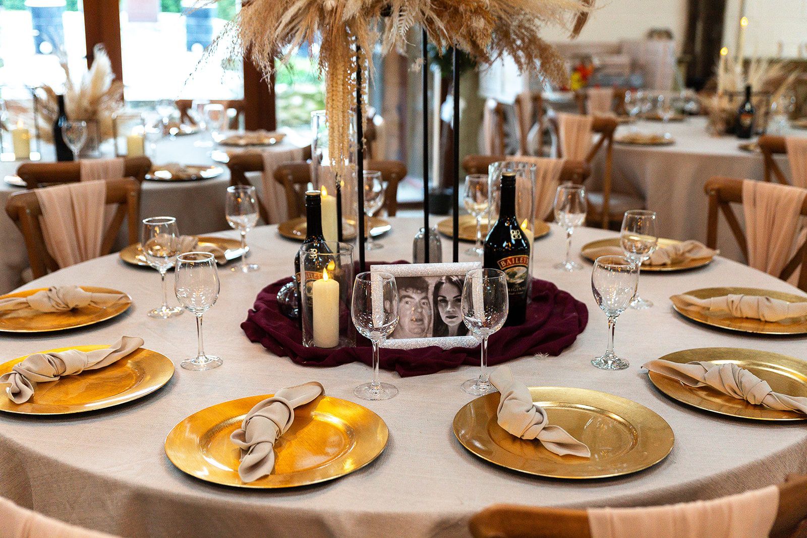 A table set for a wedding reception with plates , glasses , candles , and a centerpiece.